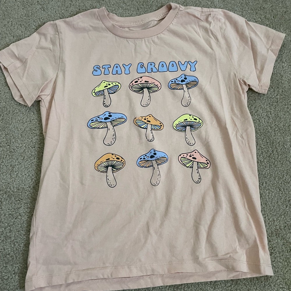 Super cute graphic tee, “Stay Groovy” in a peach color with mushrooms under